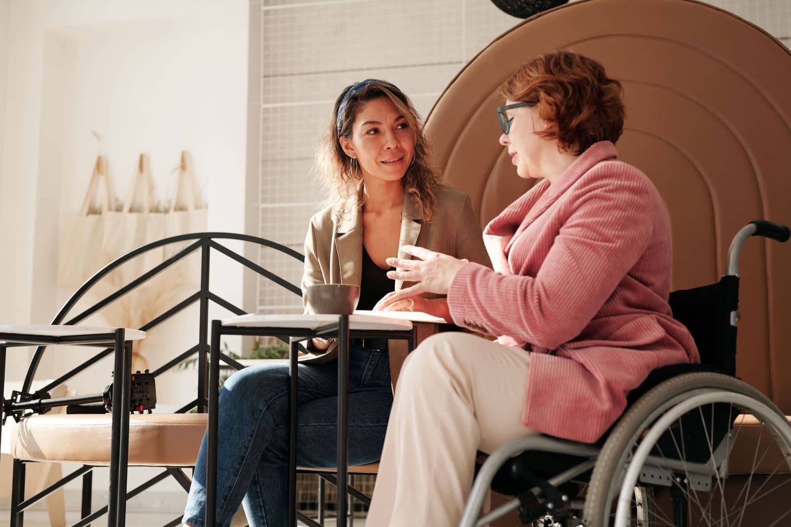 Participant using a wheelchair chatting with a support worker at a cafe