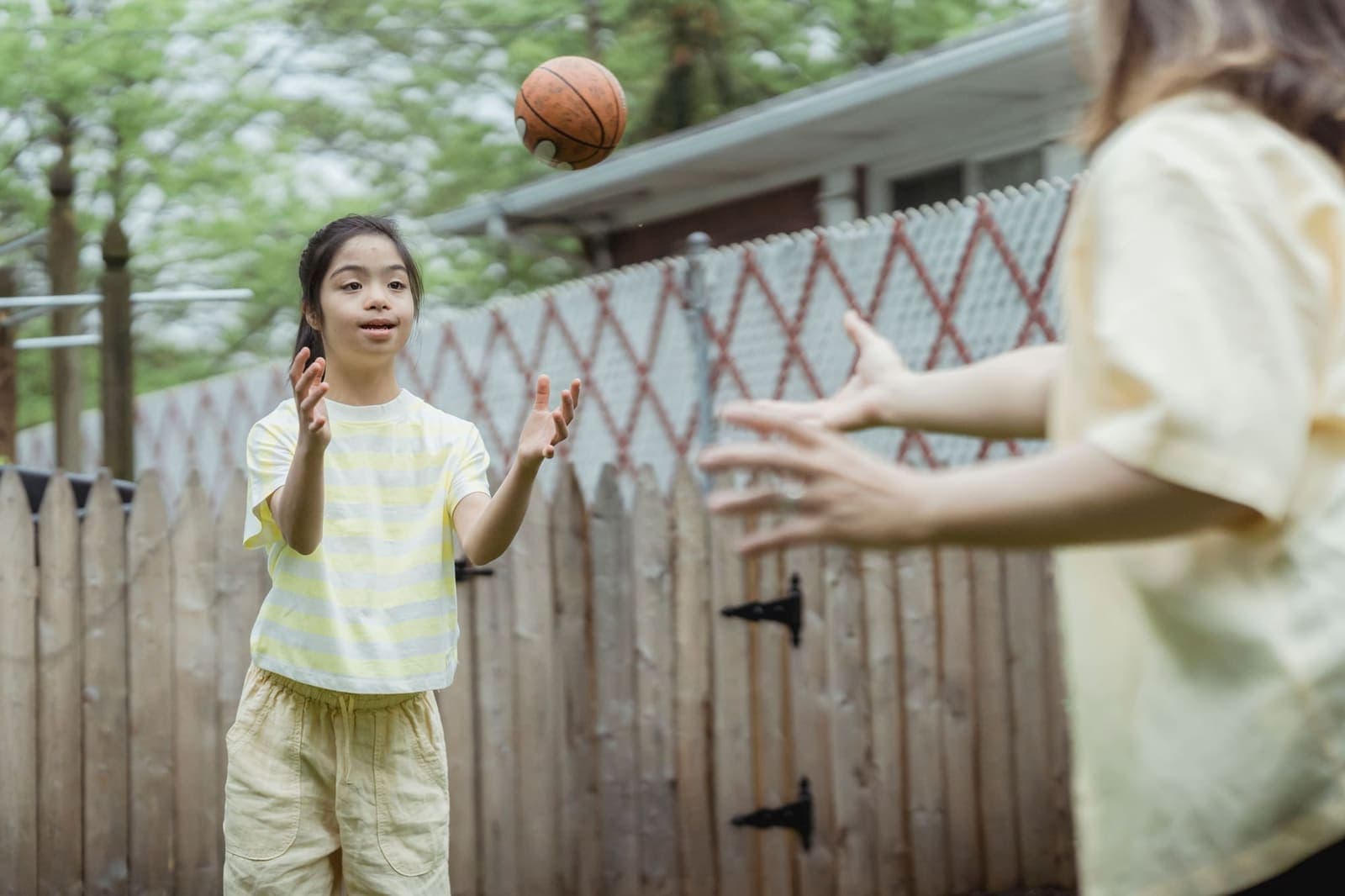 Participant playing catch with a basketball in a backyard