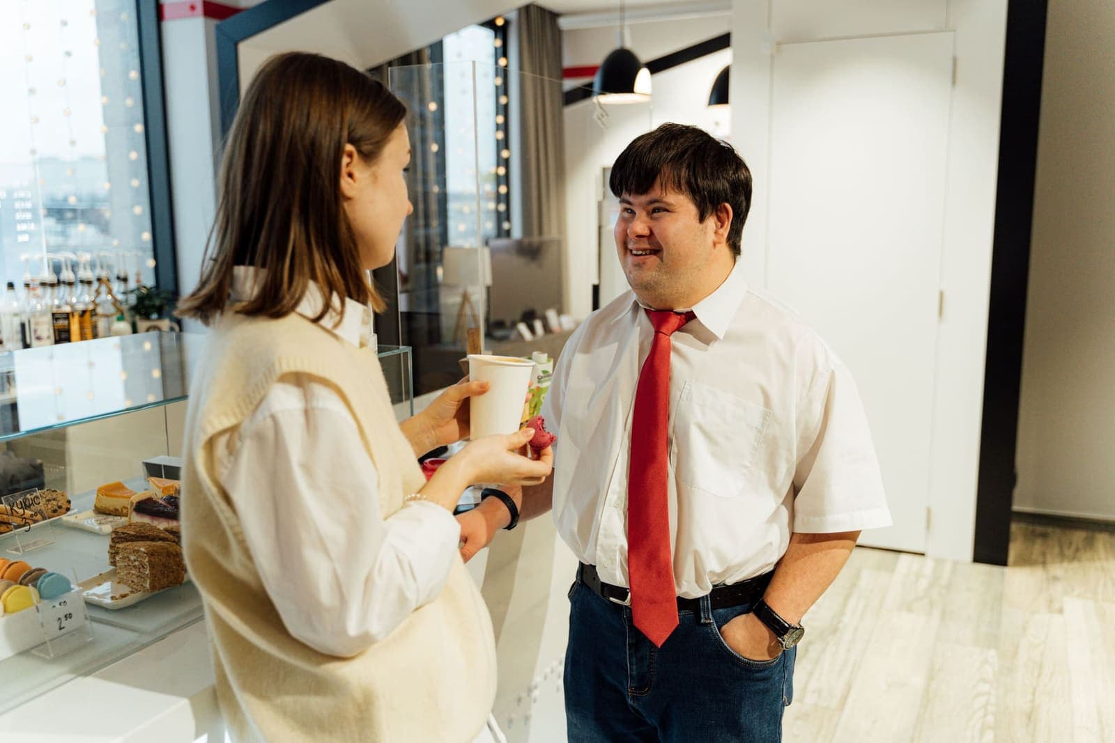 Participant and support worker chatting and smiling together at a coffee shop